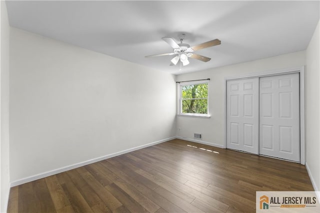 unfurnished bedroom featuring baseboards, a closet, dark wood-style floors, and ceiling fan