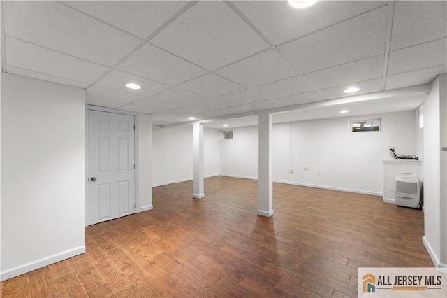 finished below grade area with wood finished floors, recessed lighting, a paneled ceiling, and baseboards