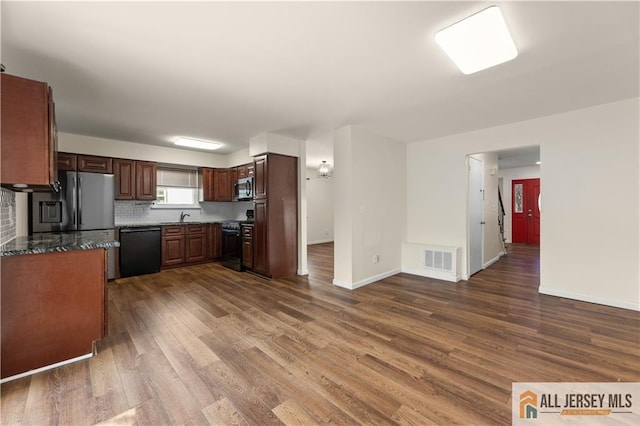 kitchen with black appliances, dark wood finished floors, a sink, backsplash, and baseboards