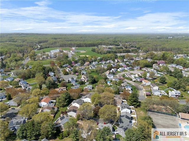 aerial view of property's location featuring a forest and nearby suburban area