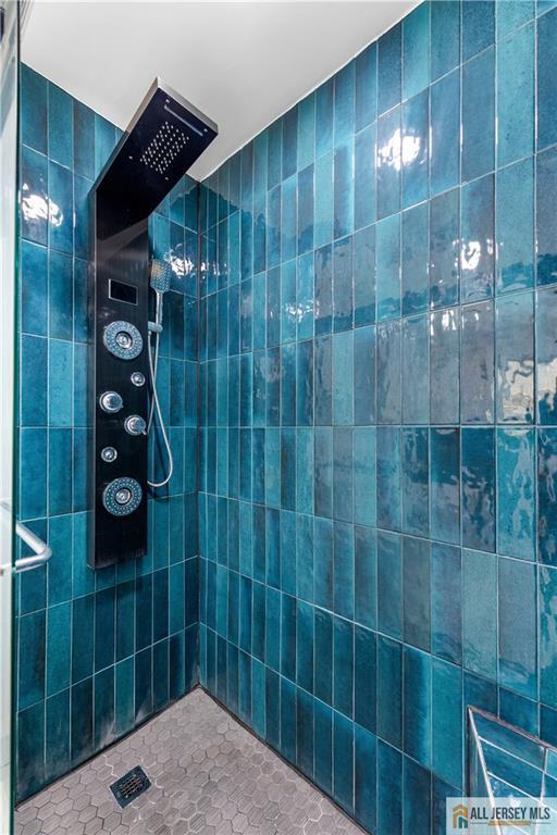 full bath featuring tiled shower, tile patterned floors, and tile walls