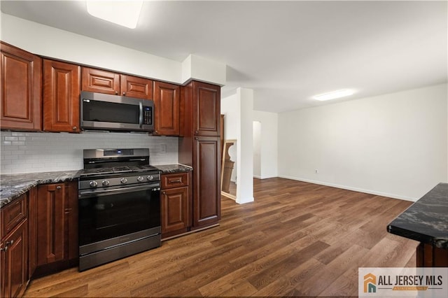 kitchen featuring stainless steel appliances, tasteful backsplash, dark wood finished floors, and baseboards
