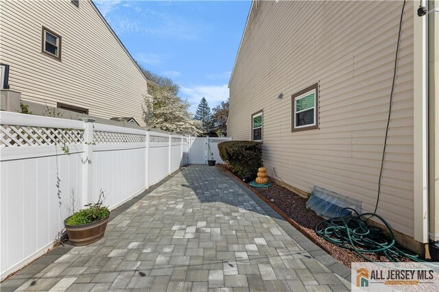 view of side of property featuring a gate, a patio area, and a fenced backyard