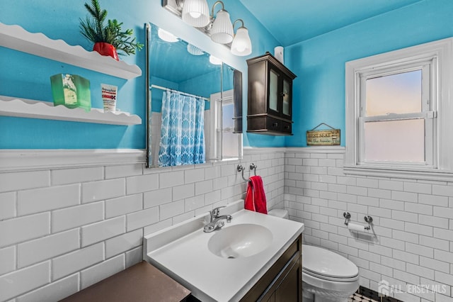 bathroom featuring vanity, a shower with curtain, wainscoting, tile walls, and toilet