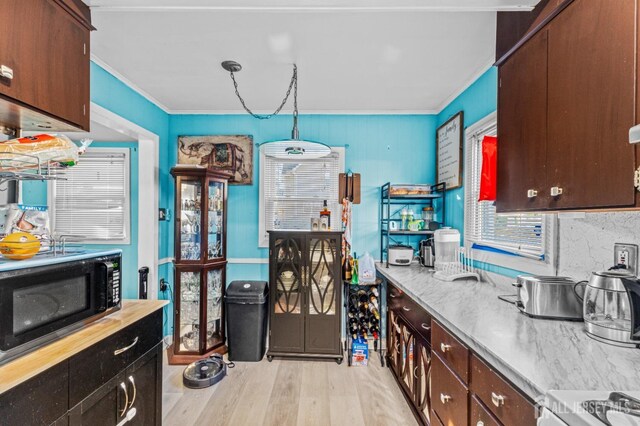 kitchen with black microwave, dark brown cabinetry, light countertops, ornamental molding, and light wood-style floors