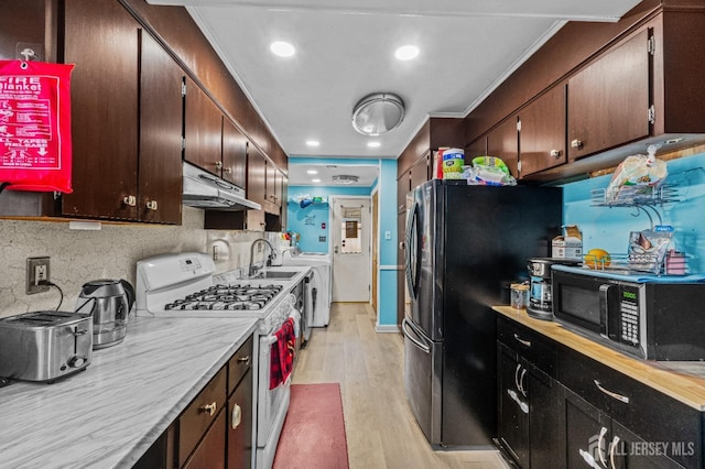 kitchen with light wood-style flooring, white gas stove, under cabinet range hood, black microwave, and light countertops