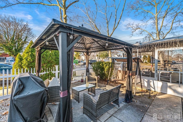 view of patio featuring a gazebo, area for grilling, fence, and an outdoor living space