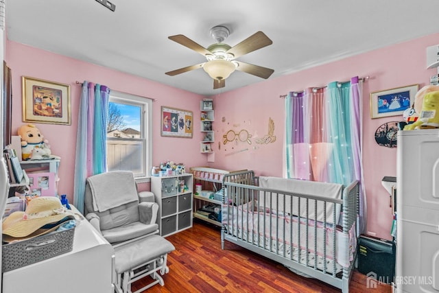 bedroom with ceiling fan, stacked washer and dryer, and wood finished floors