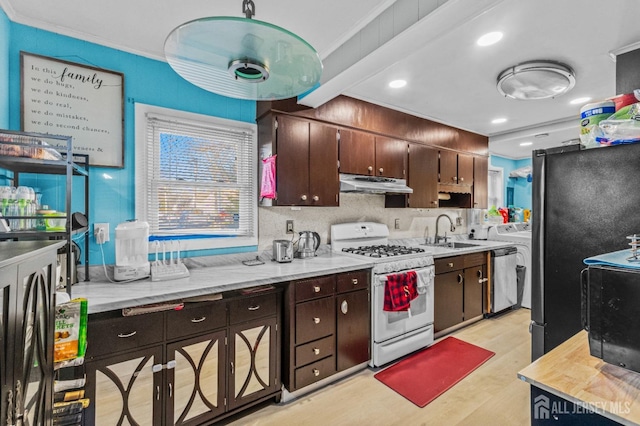 kitchen with light wood finished floors, a sink, stainless steel appliances, light countertops, and under cabinet range hood