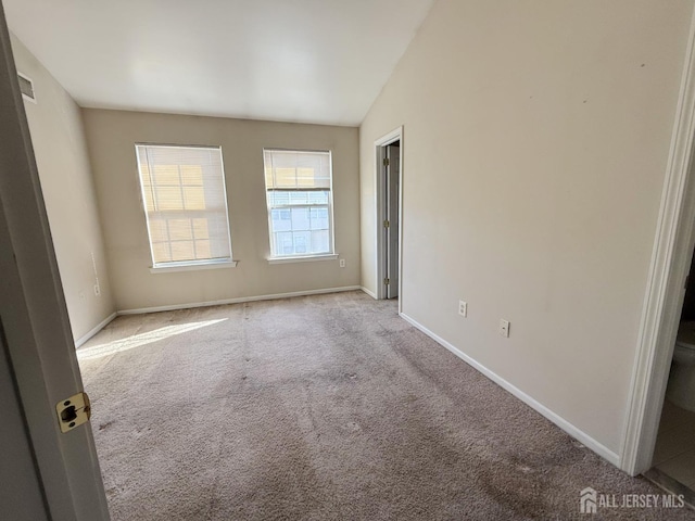 spare room with lofted ceiling and light colored carpet