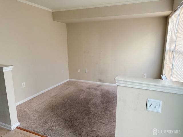 empty room with light carpet, crown molding, and baseboards