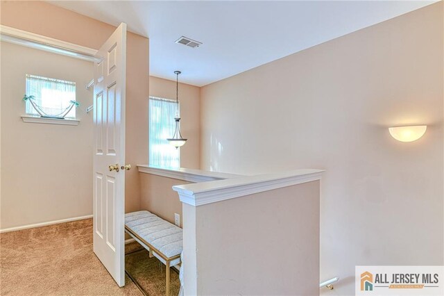 hallway with a wealth of natural light and light colored carpet