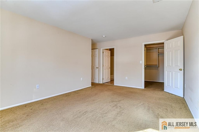 unfurnished bedroom featuring a spacious closet and carpet flooring