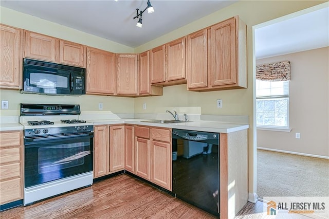 kitchen featuring light brown cabinetry, sink, black appliances, track lighting, and light wood-type flooring