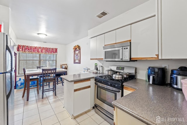 1006 Hidden Village Dr, Perth Amboy, NJ 08861 - kitchen featuring stainless steel appliances, a peninsula, white cabinets, and dark countertops