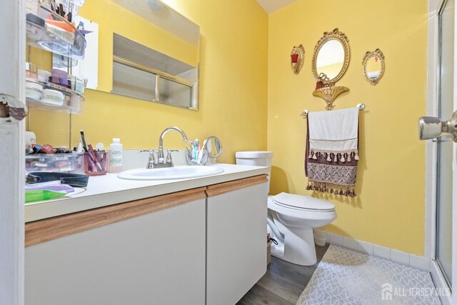 bathroom featuring hardwood / wood-style floors, vanity, toilet, and a shower with door