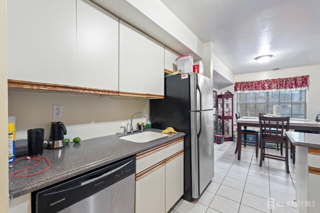 kitchen with light tile patterned flooring, white cabinetry, sink, and stainless steel appliances