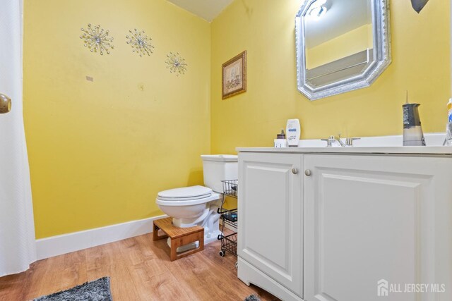 bathroom with hardwood / wood-style floors, vanity, and toilet