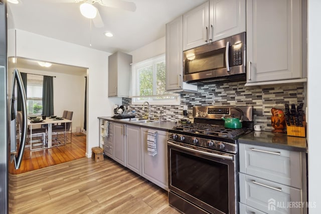 373 Rushmore Ave, Piscataway, NJ 08854 - kitchen featuring appliances with stainless steel finishes, ceiling fan, dark countertops, light wood-style floors, and backsplash