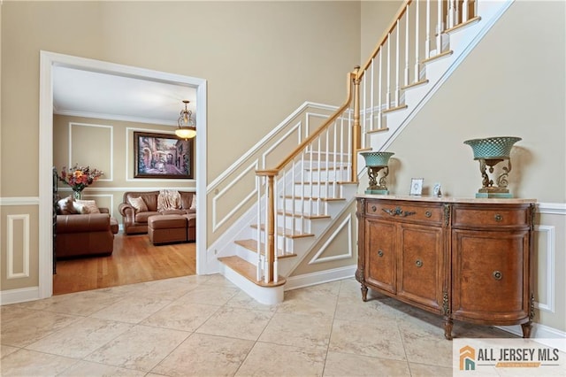 8 Adam Ct, Monroe, NJ 08831 - staircase with a decorative wall, ornamental molding, a wainscoted wall, and tile patterned flooring