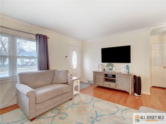 living room with visible vents, ornamental molding, baseboards, and wood finished floors