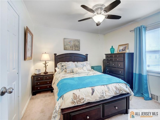 bedroom with visible vents, baseboards, light colored carpet, and ceiling fan