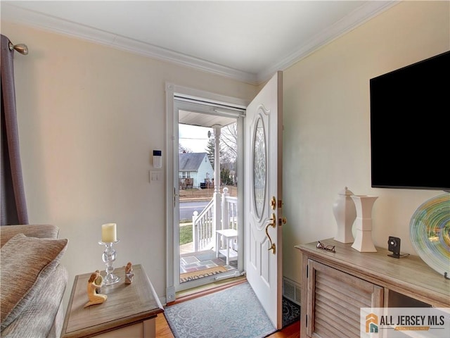 entryway with ornamental molding, wood finished floors, and visible vents