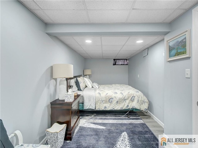 bedroom featuring a paneled ceiling, recessed lighting, baseboards, and wood finished floors