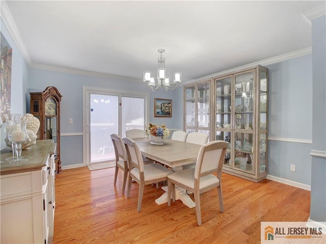 dining room with light wood-style floors, a chandelier, ornamental molding, and baseboards