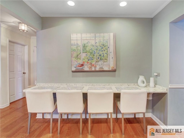 dining room featuring baseboards, ornamental molding, wood finished floors, and recessed lighting