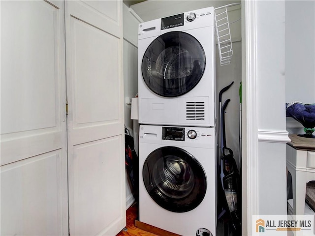 clothes washing area featuring stacked washer and clothes dryer and laundry area