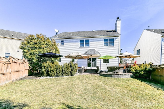 rear view of house featuring a patio, a lawn, a fenced backyard, and a chimney