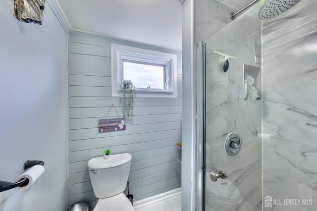 bathroom with wooden walls, a stall shower, toilet, and ornamental molding