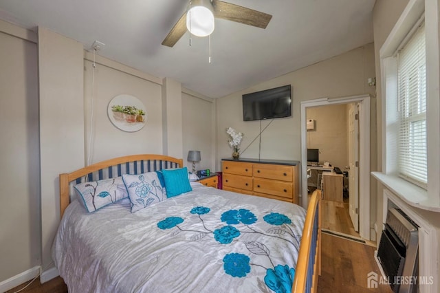 bedroom featuring wood finished floors, a ceiling fan, a wall unit AC, and vaulted ceiling