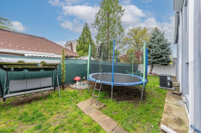 view of yard featuring cooling unit, a trampoline, and a fenced backyard