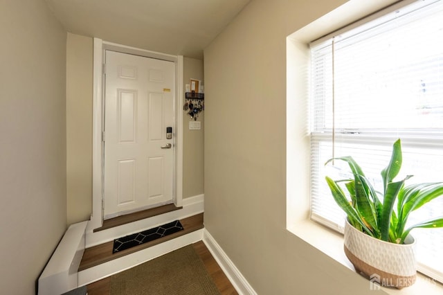 doorway with visible vents, wood finished floors, and baseboards