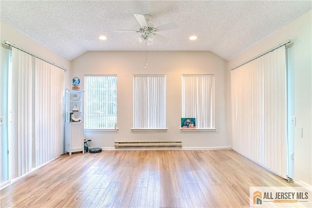 interior space with baseboard heating, vaulted ceiling, a textured ceiling, and ceiling fan