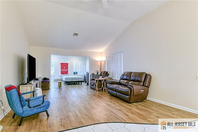 living room with light hardwood / wood-style floors, a textured ceiling, and lofted ceiling