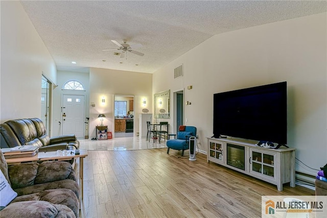 living room featuring a textured ceiling, ceiling fan, vaulted ceiling, and hardwood / wood-style floors