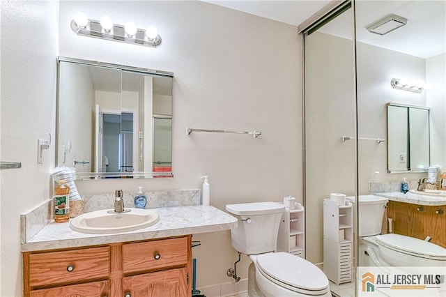 bathroom with toilet, tile patterned flooring, and vanity