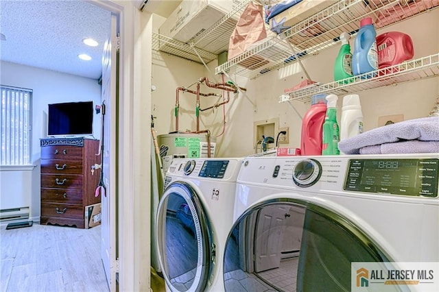 laundry room with electric water heater, a baseboard heating unit, light hardwood / wood-style flooring, washer and clothes dryer, and a textured ceiling