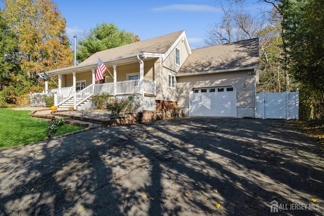 view of property exterior with aphalt driveway, a porch, and an attached garage