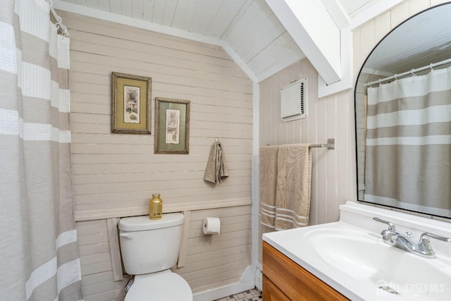 bathroom featuring toilet, curtained shower, wooden walls, vanity, and vaulted ceiling