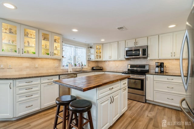 kitchen featuring visible vents, white cabinetry, stainless steel appliances, light wood-style floors, and butcher block counters