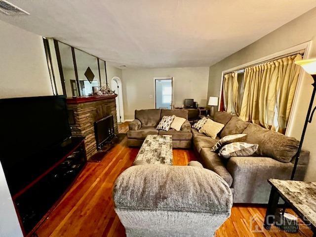 living area with visible vents, a fireplace, and wood finished floors