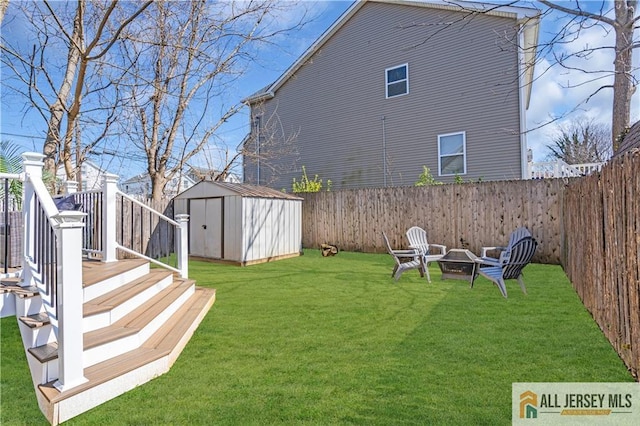 view of yard featuring a fenced backyard, a storage unit, an outbuilding, and a fire pit