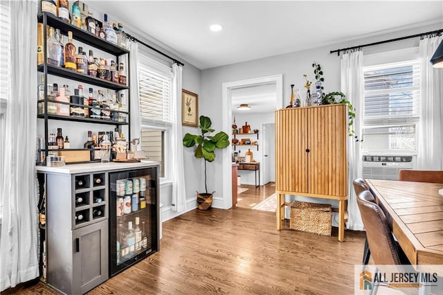 bar featuring cooling unit, recessed lighting, baseboards, wood finished floors, and a bar