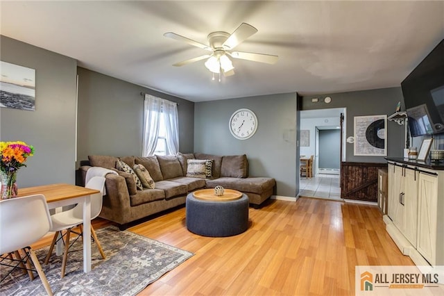 living room featuring ceiling fan, light wood-type flooring, baseboard heating, and baseboards