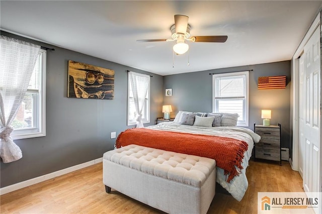 bedroom featuring light wood-style flooring, a closet, multiple windows, and baseboards