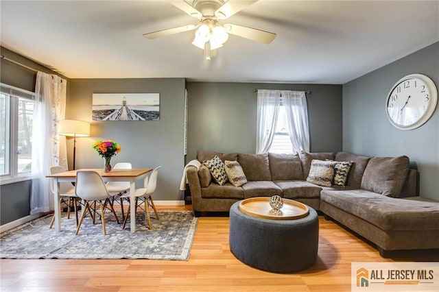 living room with healthy amount of natural light, wood finished floors, and a ceiling fan
